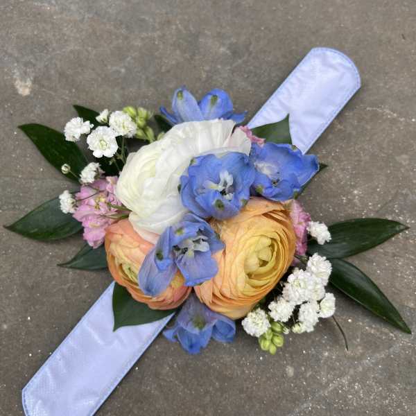 Hand-tied bouquet with blue, white, and peach flowers on a pale ribbon