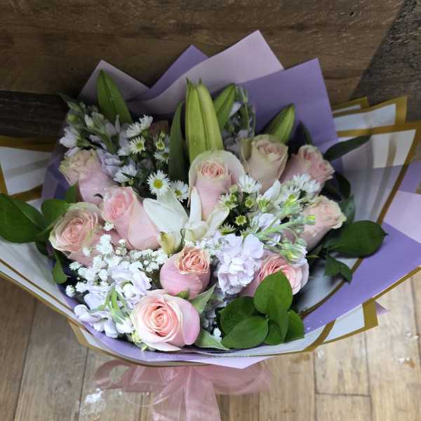 Bouquet of pale pink roses and white lilies with lavender wrapping