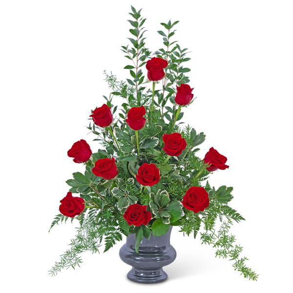 Red roses arranged in a clear glass vase with greenery