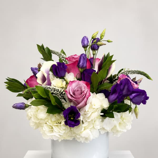 Pink and purple mixed flowers arranged in a clear glass vase