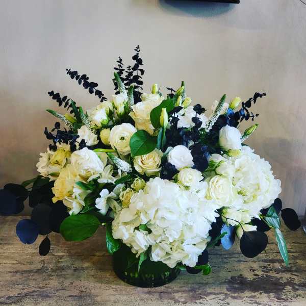 White rose and hydrangea arrangement in a low black vase