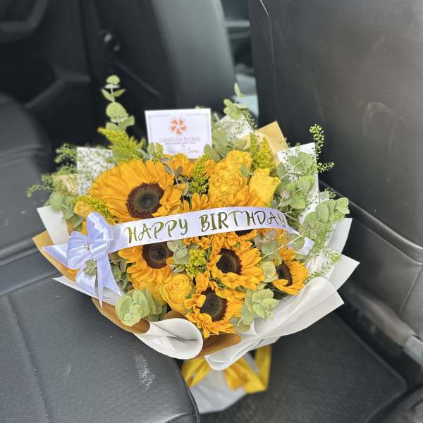Sunflower bouquet with yellow roses and a birthday ribbon in a car seat
