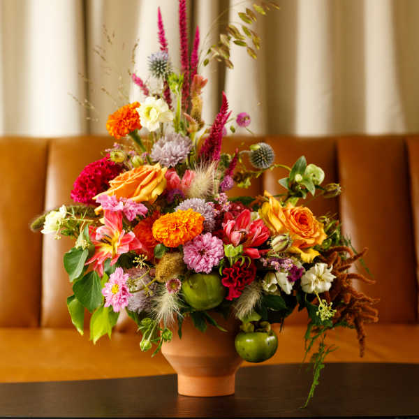 Colorful mixed flower arrangement in a terracotta vase on a table