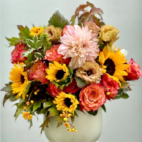 Mixed bouquet of sunflowers, roses, and a pale dahlia in a white vase