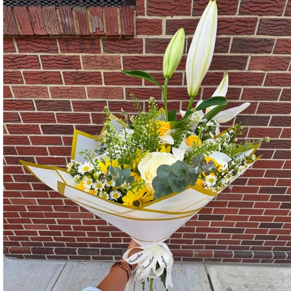 Handheld bouquet with white lilies, roses, and yellow flowers wrapped in white paper
