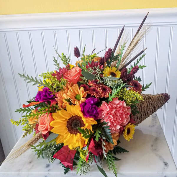 Colorful bouquet with sunflowers, roses, and carnations in a woven cone wrap