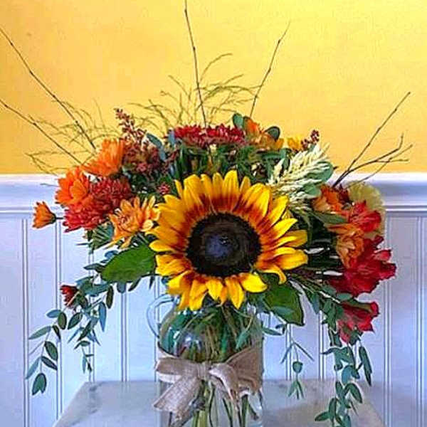 Sunflower bouquet in a glass vase with orange and red flowers