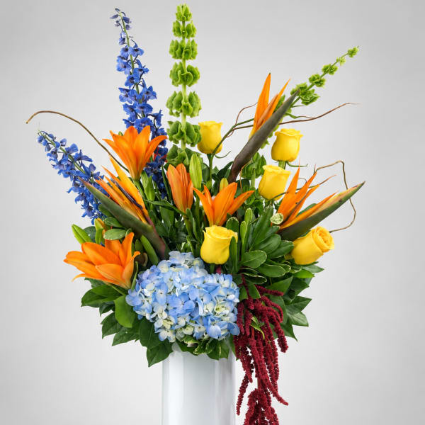 Colorful tropical bouquet in a tall white vase