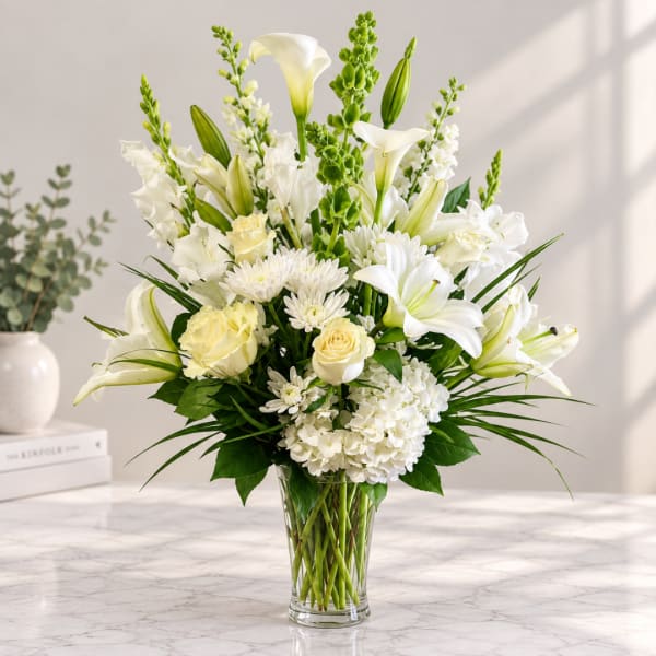 White lilies, roses, and chrysanthemums arranged in a clear glass vase