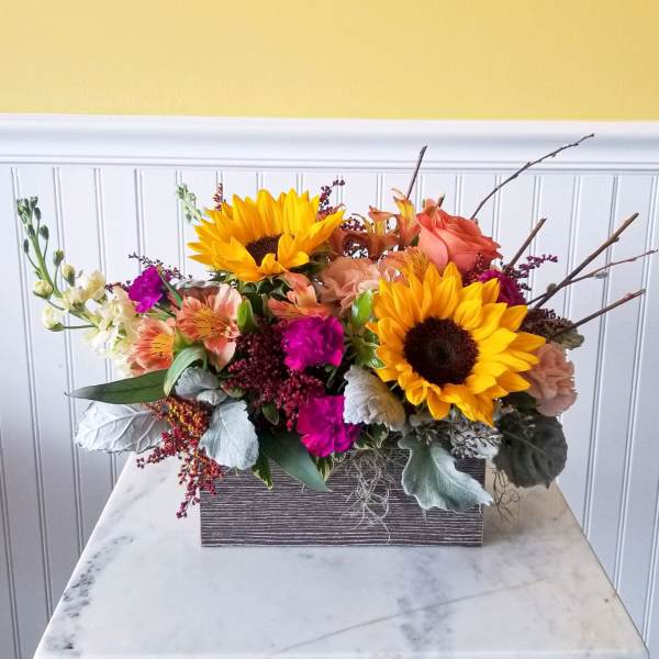 Mixed bouquet with sunflowers, peach roses, and magenta flowers in a rectangular box