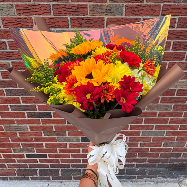 Bright mixed bouquet of sunflowers and daisies wrapped in brown paper