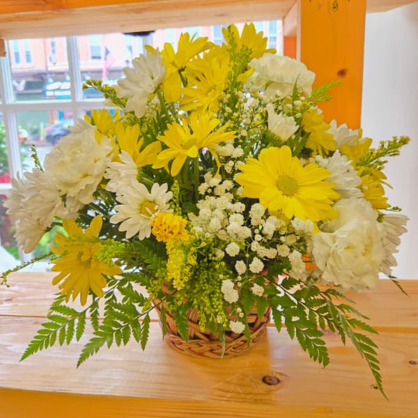 Yellow and white daisy bouquet in a woven basket