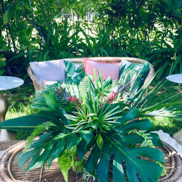 Tropical plant arrangement in a woven basket on a patio table