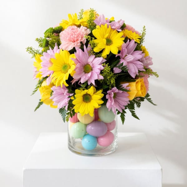 Bouquet of yellow and lavender daisies in a glass vase with pastel eggs