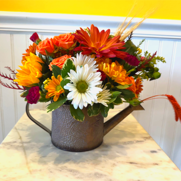 Mixed orange, white, and yellow flowers arranged in a metal watering can