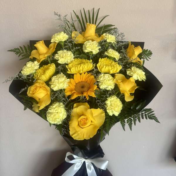 Yellow rose and carnation bouquet with a sunflower, wrapped in black paper