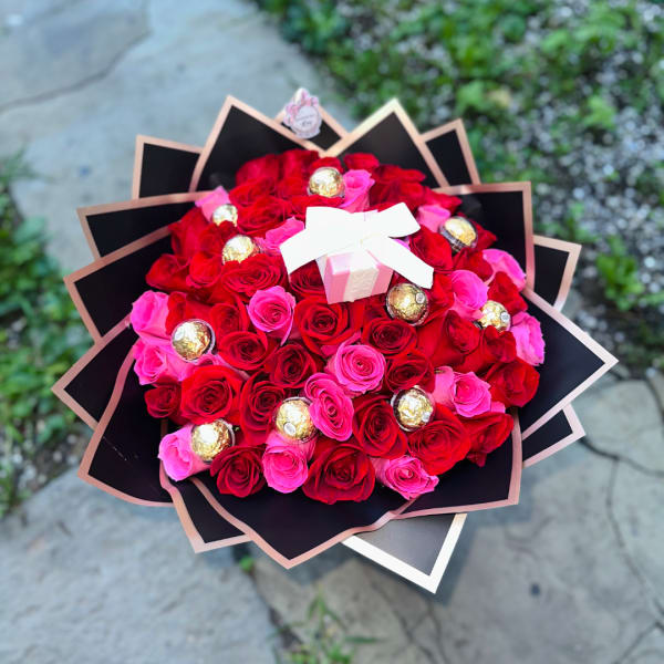 Bouquet of red and pink roses with gold-wrapped chocolates and a white bow