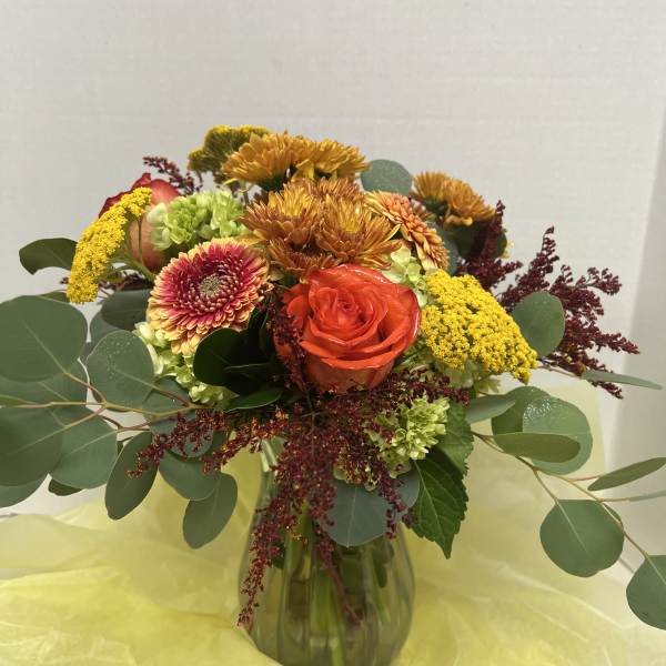 Mixed bouquet in a glass vase with orange roses and yellow chrysanthemums