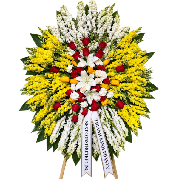 Large standing floral wreath with red, white, and yellow flowers on ribbons