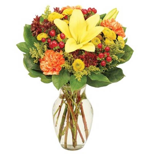 Yellow lily bouquet with orange and red flowers in a clear glass vase