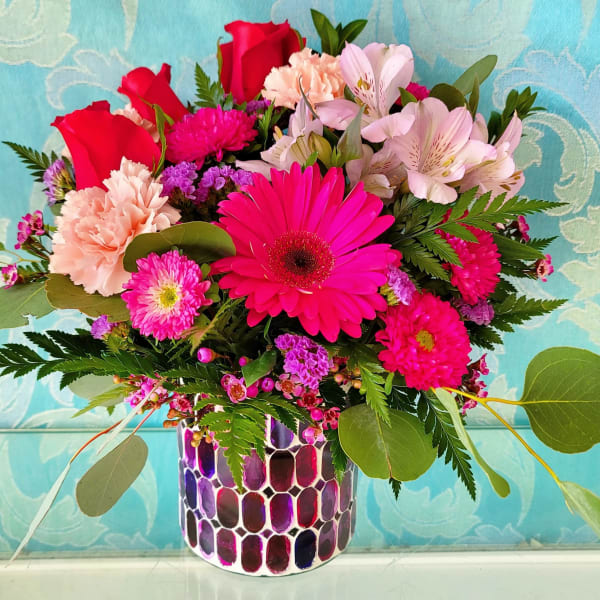 Mixed bouquet of pink and red flowers in a patterned vase