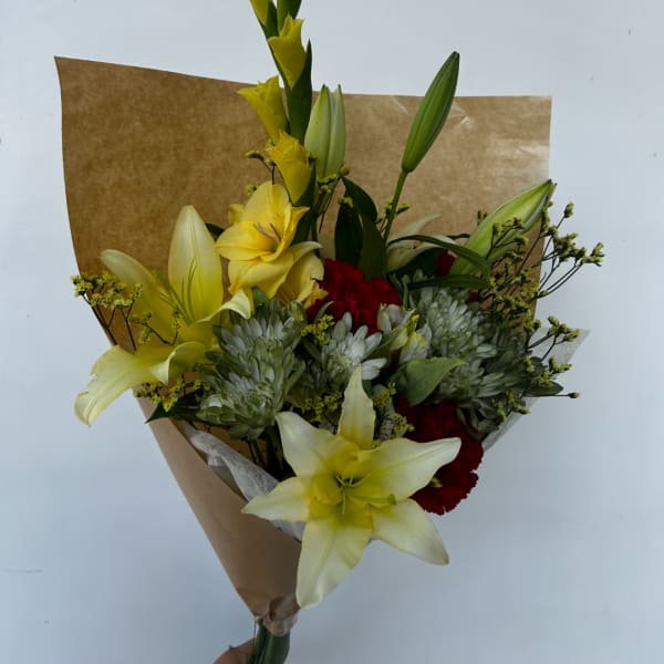 Bouquet of yellow lilies, red carnations, and white chrysanthemums in brown paper