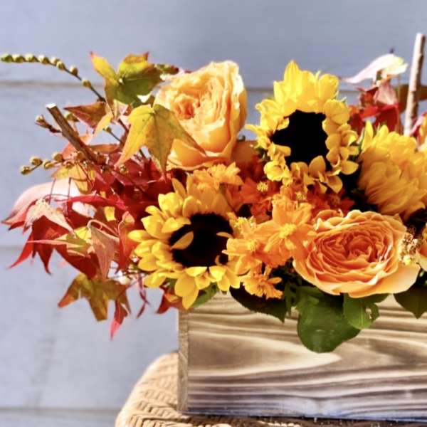 Autumn bouquet of yellow sunflowers and orange roses in a striped vase