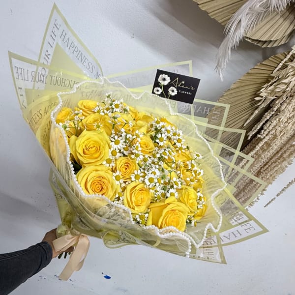 Yellow roses and small white daisies in wrapped bouquet