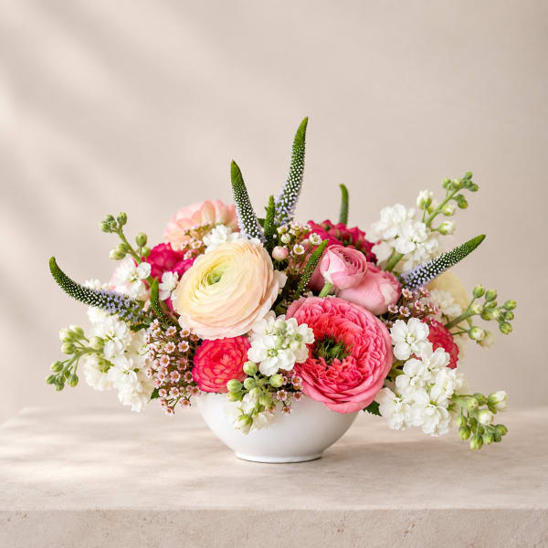 Pink and white mixed flower arrangement in a white bowl vase