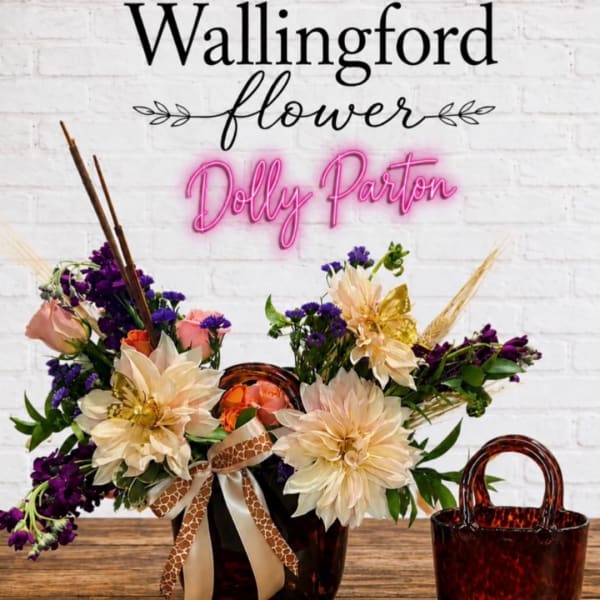 Arrangement of cream and purple flowers in a tortoiseshell vase with ribbon