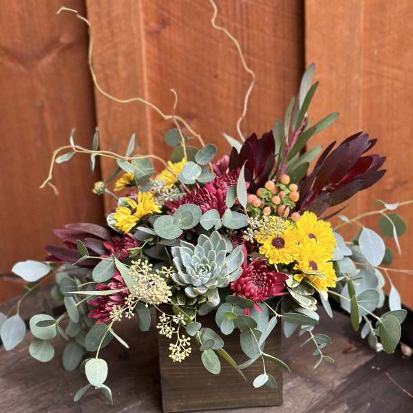 Mixed bouquet with yellow daisies, burgundy blooms, and a succulent in a wooden box