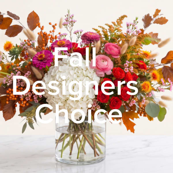Mixed fall bouquet in a clear glass vase with white hydrangea and red, pink, and orange flowers