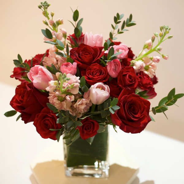 Red and pink roses arranged in a clear glass vase