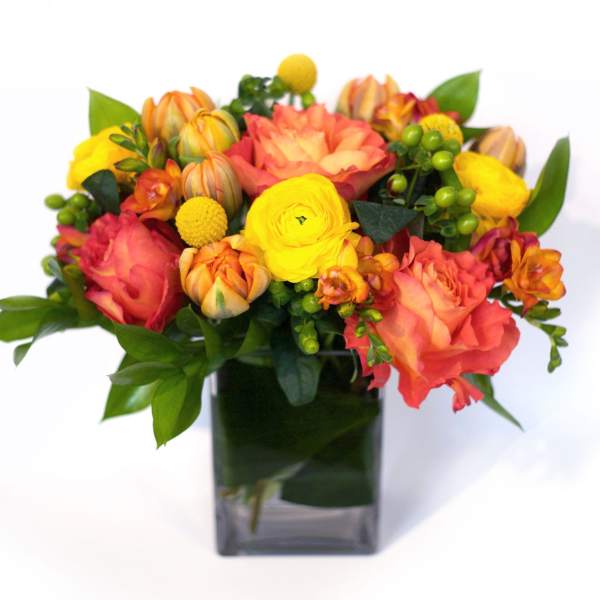 Orange and yellow mixed bouquet in a square glass vase