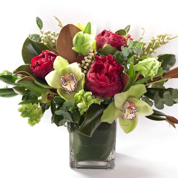 Bouquet of red and green flowers in a clear square vase