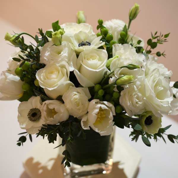 White roses and anemones arranged in a clear glass vase