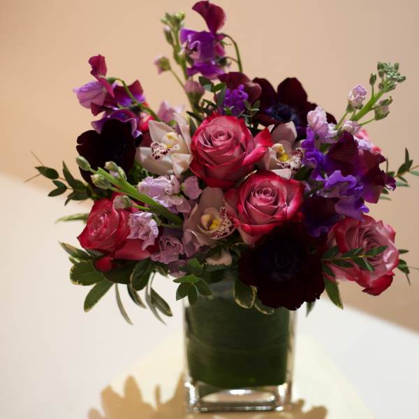 Mixed bouquet of pink, purple, and white flowers in a clear glass vase