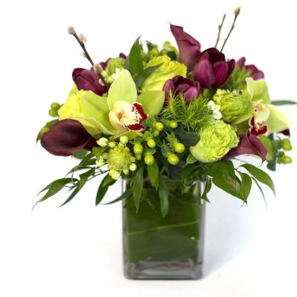 Bouquet of green and burgundy flowers in a square glass vase