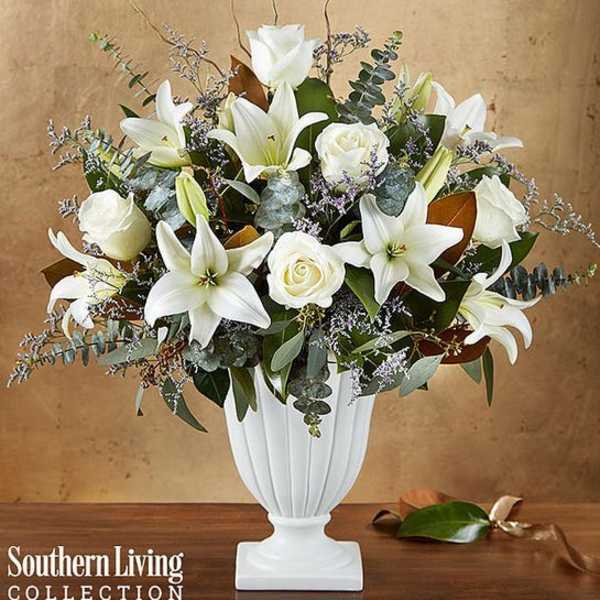 White lilies and roses arranged in a white pedestal vase