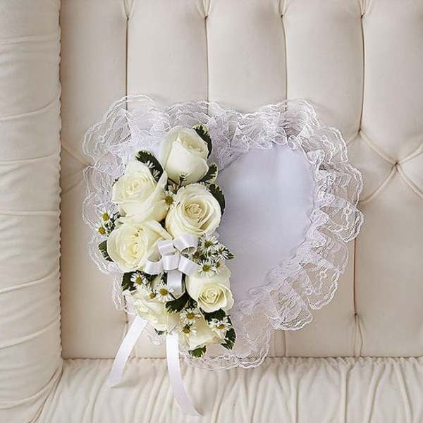 White rose bouquet with lace trim and ribbon on a cream tufted chair