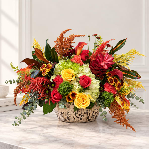 Colorful mixed flower arrangement in a patterned basket on a table