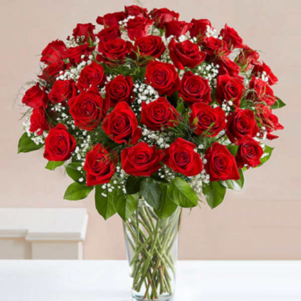 Red roses arranged in a clear glass vase with white filler flowers