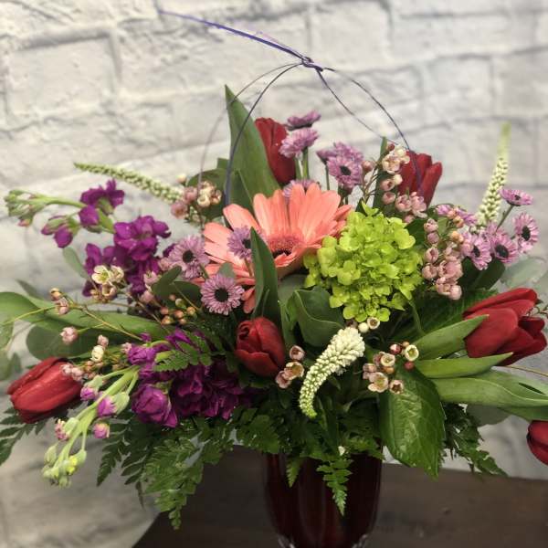 Mixed bouquet in a dark glass vase with pink and red flowers