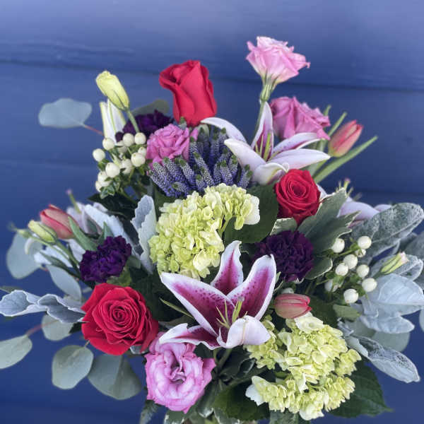Mixed bouquet of roses, lilies, and hydrangeas in a glass vase