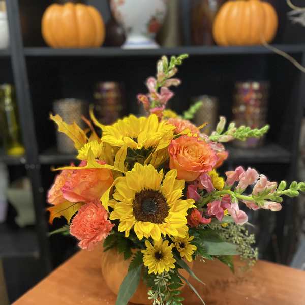 Autumn bouquet with sunflowers, orange roses, and pink snapdragons in a pumpkin vase