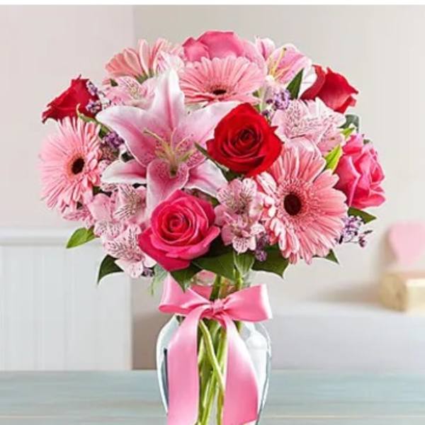 Pink and red mixed bouquet in a glass vase with a pink ribbon