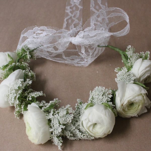 White flower crown with lace ribbon on a brown background