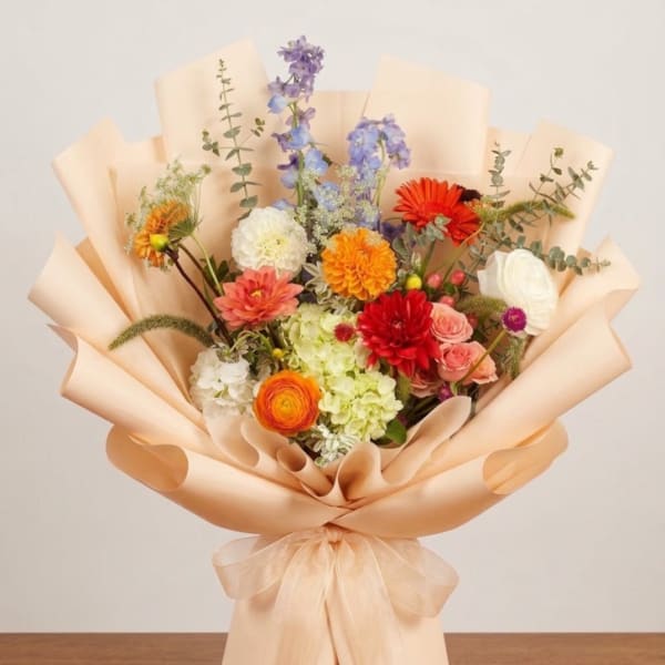 Colorful mixed bouquet wrapped in peach paper with a bow