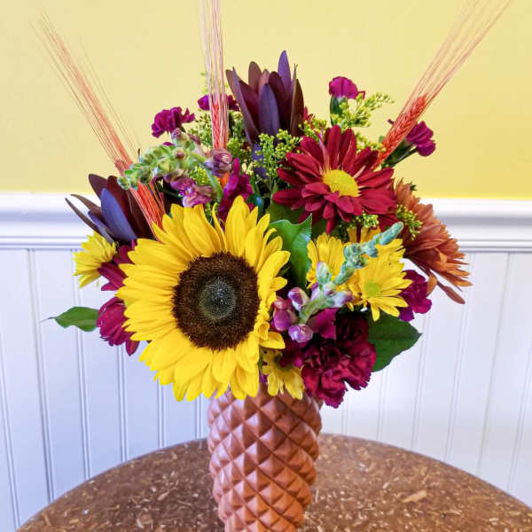 Mixed bouquet with sunflowers and burgundy blooms in a textured vase