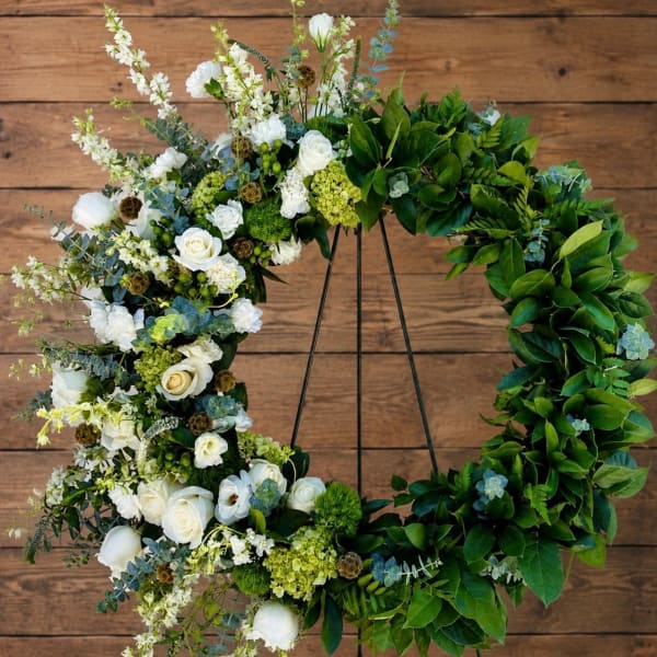 Large floral wreath with white flowers and green foliage on a stand